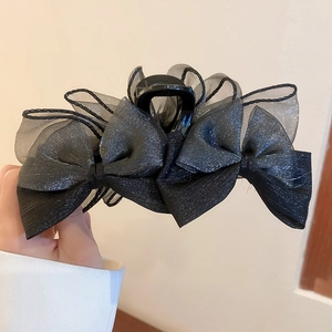 Détail d'une grande pince à cheveux nœud noir avec des couches de tulle pailleté