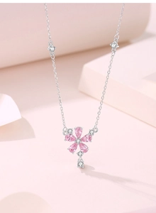 Macro detail of silver necklace featuring pink drop-shaped gemstone flower pendant