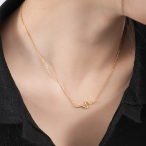 Detailed view of a gold snake pendant necklace with white diamonds on a woman's neck