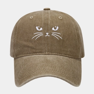 Close-up of cat embroidery and washed cotton texture on a khaki baseball cap