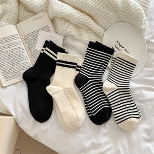 Flat lay of four pairs of warm wool blend socks in solid black, cream, and striped patterns