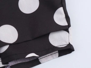 Detail eines weißen Polka-Dot-Musters auf schwarzem Stoff mit sauberen Nähten