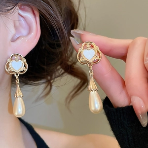 Detail of vintage heart pearl drop earrings featuring gold filigree and teardrop pearls