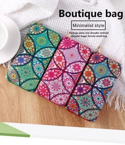 Three ethnic long wallets with colorful mandala patterns displayed on a wooden table