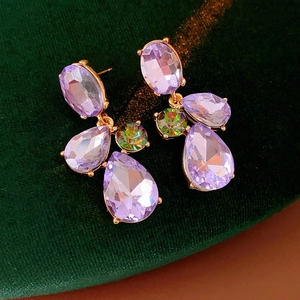 Close-up of vintage geometric teardrop earrings with purple and iridescent crystals