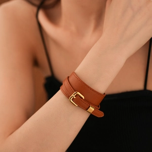 Detail of brown faux leather double wrap bracelet with polished gold metal buckle closure
