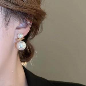 Detailed close-up of double white pearl earrings with golden bar on a female model