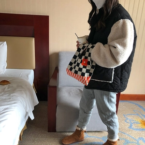 Knitted checkerboard tote bag with orange flower detail in a lifestyle setting