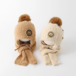 Detail der weichen Winter-Strickmütze mit Ohrenklappen und Plüschpompon für Kinder