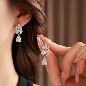Detail of silver wheat ear and teardrop earrings with white zircon on ear model