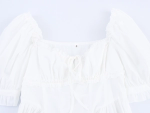 Detail des eckigen Ausschnitts mit Puffärmeln und Schleife am weißen Maxikleid
