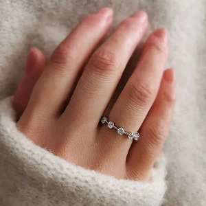 Close-up of slim silver ring with five micro-set zircons worn against beige knitwear