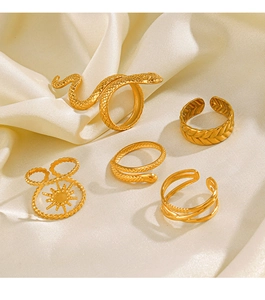 Detail of five-piece gold snake rings and sun pattern bands on cream silk fabric
