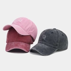 Detailed view of washed cotton baseball caps in pink, burgundy, and black with dog embroidery