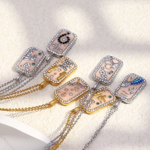Detail of 18K gold zodiac square pendants with colorful enamel and inset crystals