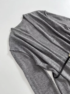 Detail shot of grey wool knit cardigan featuring fine texture and slim black waist belt