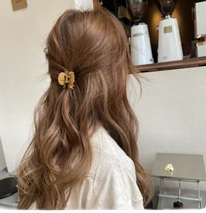 Piccola molletta per capelli giallo senape opaco su una coda di cavallo in un caffè