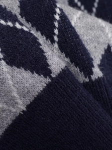 Close-up of the thick diamond argyle knit fabric with soft wool texture on v-neck sweater