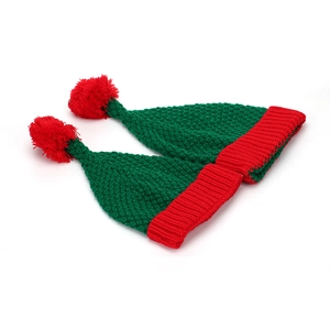 Détail de deux bonnets de Noël tricotés rouge et vert avec pompons sur fond blanc uni