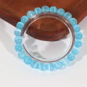 Sky blue cat eye stone beaded bracelet with luminous effect on a wooden tray