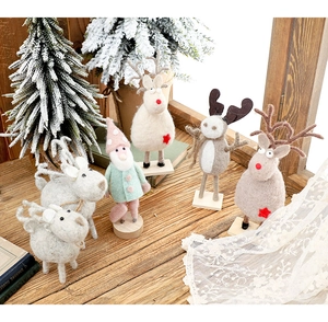 Detailed view of handcrafted wool felt Christmas reindeer and Santa figurines on wood table