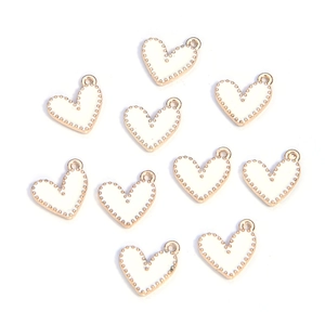 Flat lay of white enamel heart charms with gold beaded edges for DIY jewelry making