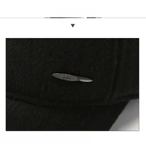 Detail of black winter baseball cap showing wool texture and oval metal decoration