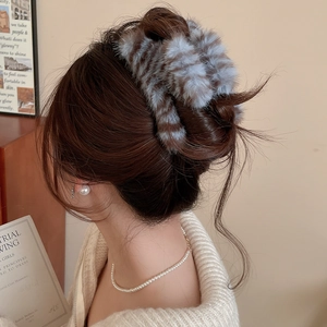 Détail d'une grande pince à cheveux en peluche rayée tenant un chignon élégant