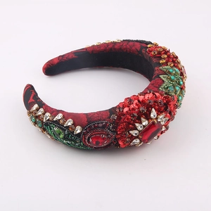 Detailed close-up of a sponge headband featuring red rhinestones and green leaf embroidery
