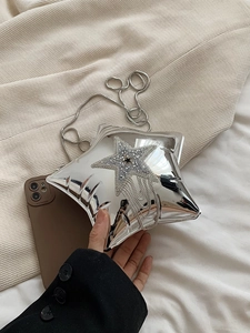 Macro shot of silver star-shaped clutch bag with sparkling rhinestone tassels and chain