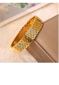 Macro detail of gold-plated hollow bangle with lattice engraving and zircon stones