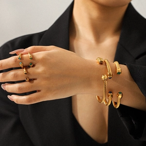 Detailed view of gold spiral cable bracelets and rings set with colorful gemstones