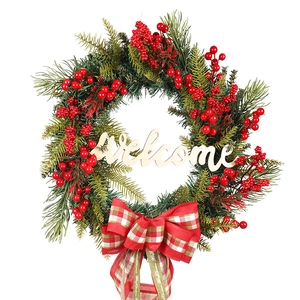 Christmas wreath with green pine needles, red berries and wooden Welcome sign