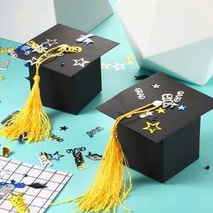 Miniature graduation cap candy boxes with yellow tassels and celebratory decorations