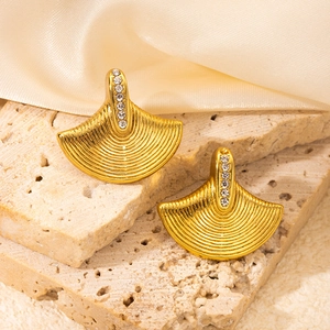 Detail of fan-shaped golden stud earrings featuring brushed texture and zircon stones