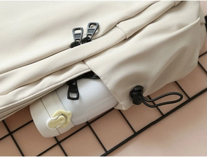 Close-up of beige backpack side pocket with adjustable drawstring and durable fabric