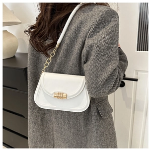 Close-up of white leather shoulder bag with elegant gold hardware and chain strap
