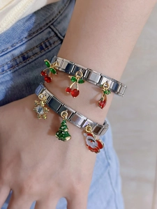 Close-up of Italian modular charm bracelets with red cherry and Christmas enamel pendants