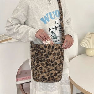 Detail showing high capacity leopard print plush shoulder bag with phone being inserted