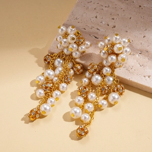 Macro detail of gold tassel earrings featuring white pearls and rhinestone spheres