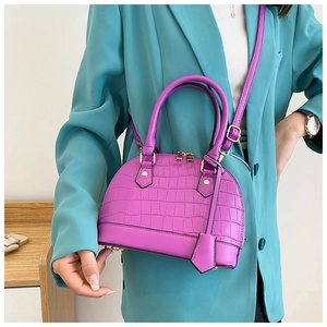 Close-up of purple faux leather shell bag with crocodile texture and gold hardware