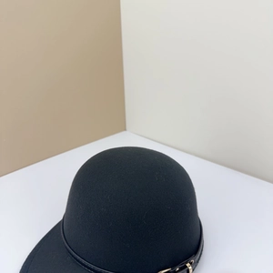 Détail de la casquette en laine noire avec lanière en cuir et boucle métallique
