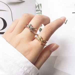 Detailed view of silver and gold knotted stainless steel rings worn by a fashion model