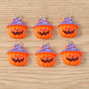 Detailed close-up of orange pumpkin charms with purple glitter wizard hats for jewelry DIY