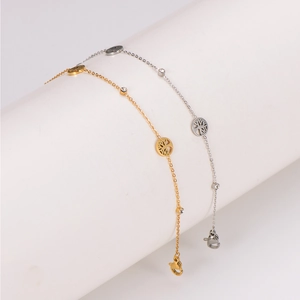 Elegant gold and silver tree of life anklets with sparkling cubic zirconia on white stand
