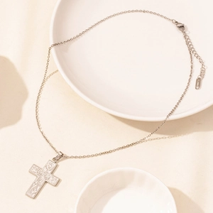 Detailed macro view of a silver stainless steel cross pendant with intricate floral engravings