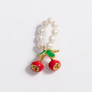 Detail of a pearl ring with a red cherry charm featuring golden stems and green leaves