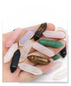 Detailed view of hand holding polished double-terminated hexagonal crystal quartz pillars