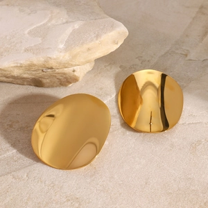 Detailed close-up of polished gold oval concave geometric stud earrings on stone