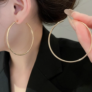 Detail of large minimalist gold hoop earrings showing smooth finish and sleek open design